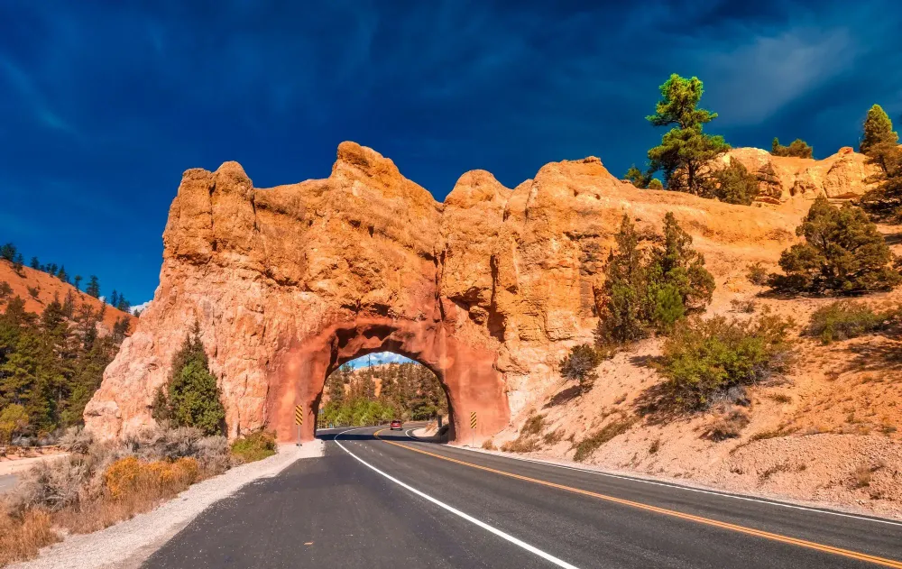 Road running under stone arch at the entrance of Bryce Canyon National Park